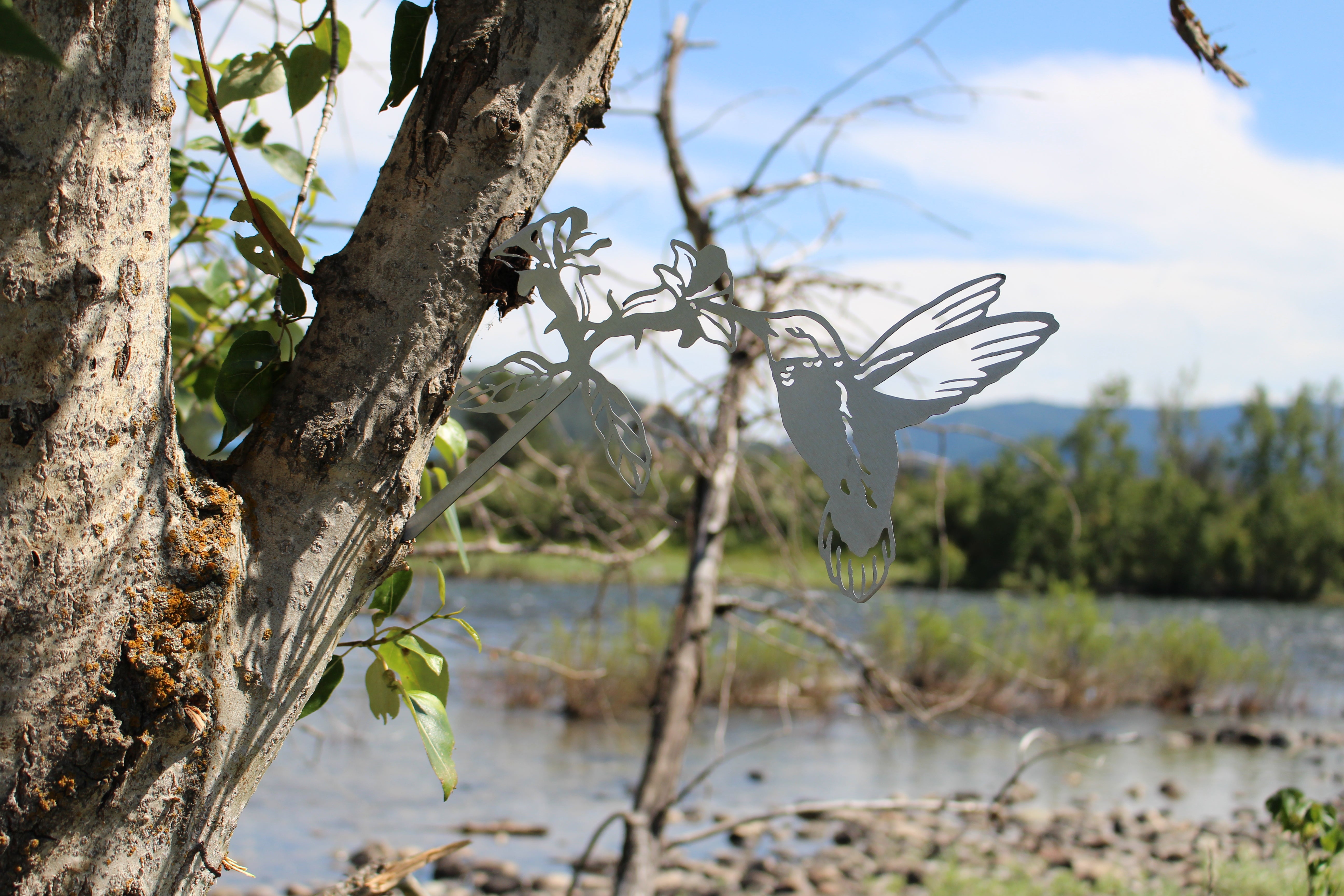 Metal hummingbird tree stake sipping from flower, rustic steel garden decoration for outdoor yard or planter