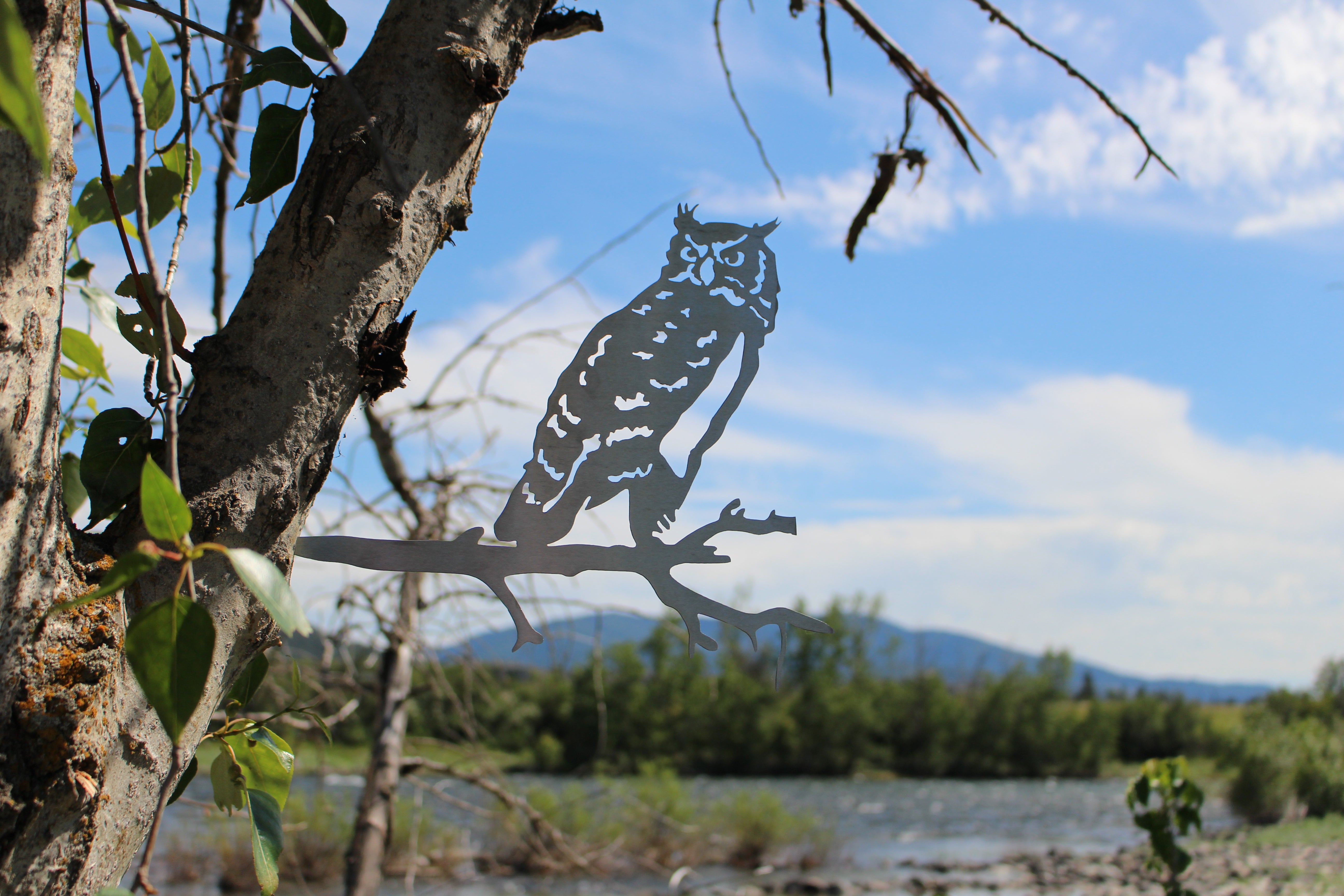 Metal owl tree stake perched on branch, rustic steel garden decoration for outdoor yard or lawn