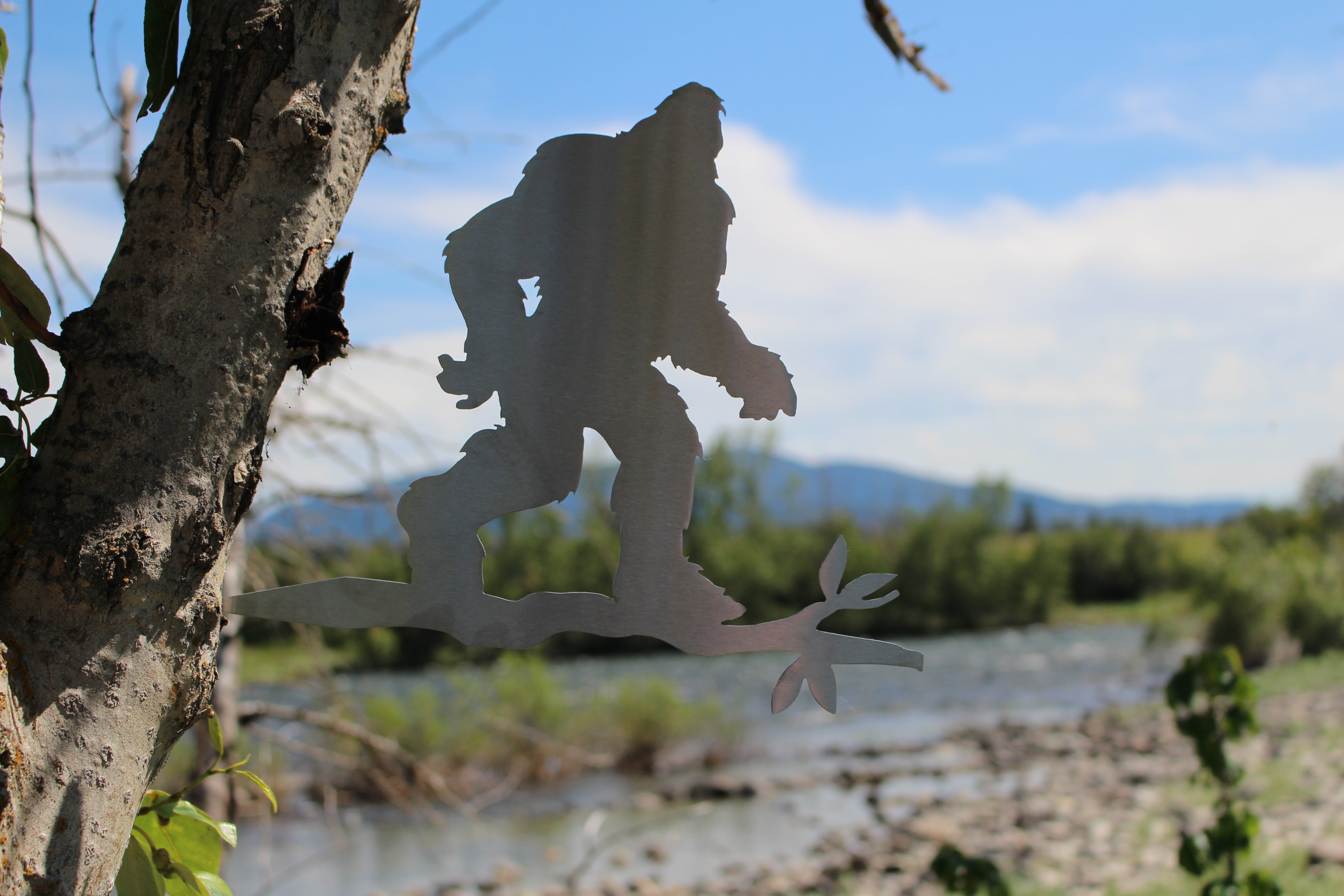 Metal sasquatch tree stake on branch, rustic steel Bigfoot garden decoration for outdoor yard or lawn