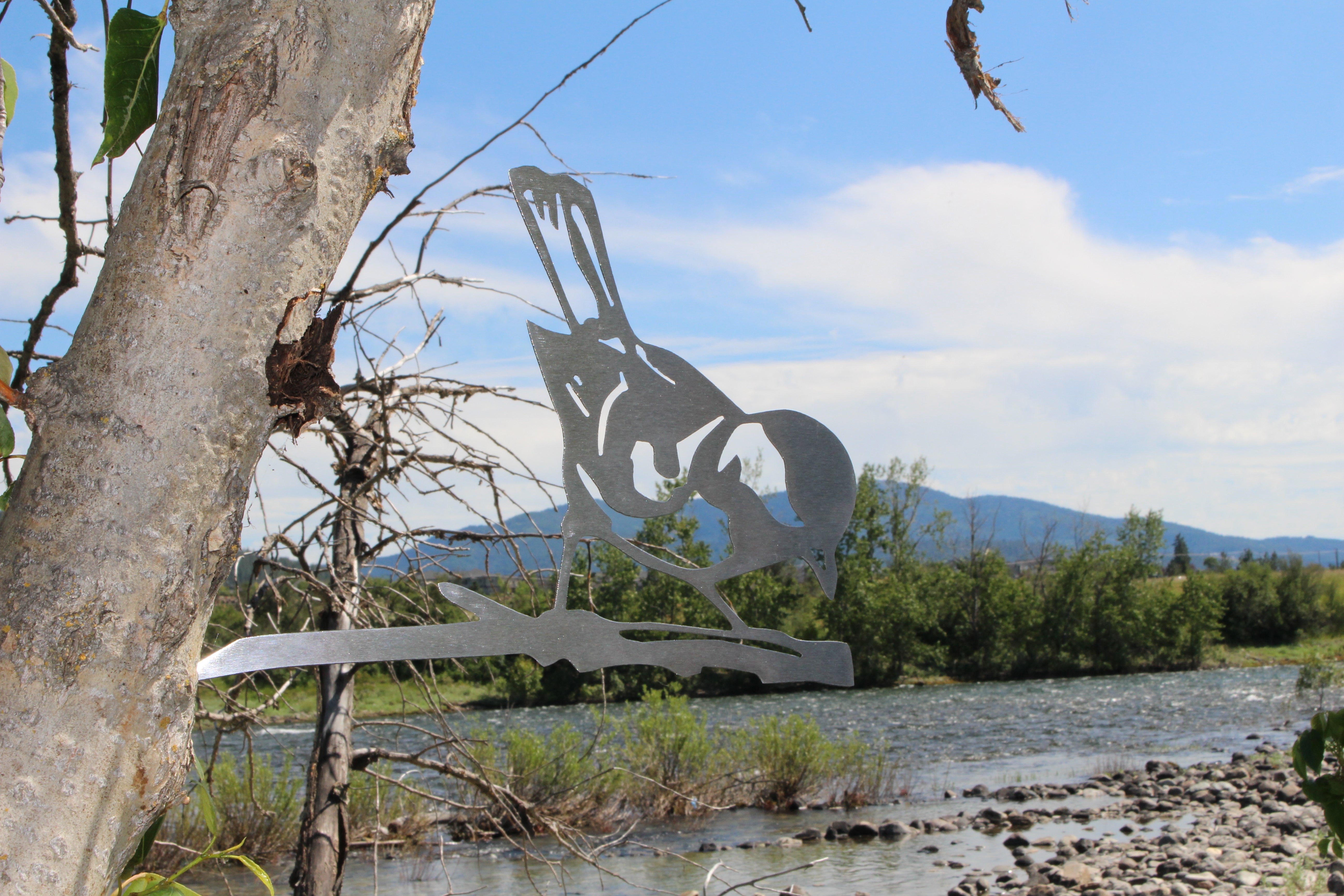 Metal finch bird tree stake perched on branch, rustic steel garden decoration for outdoor yard or flower bed