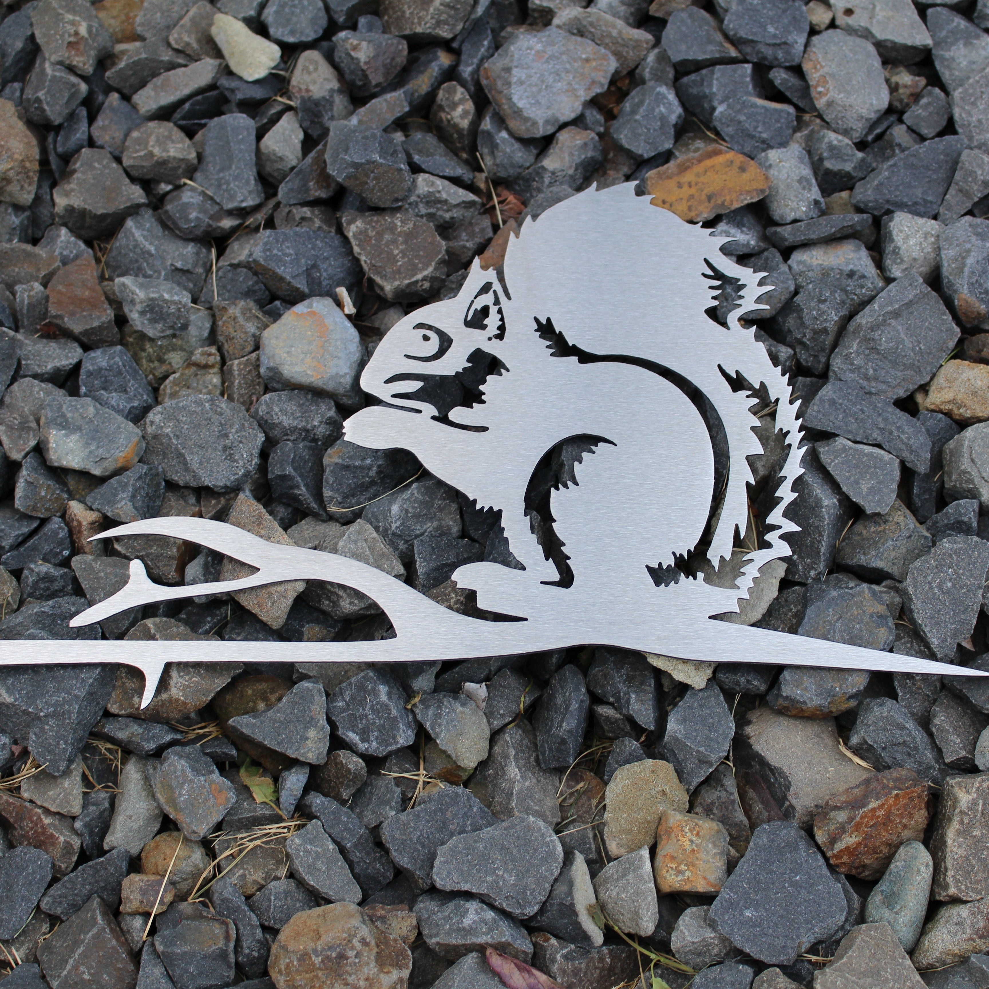 Metal squirrel tree stake on branch, rustic steel garden decoration for outdoor yard or flower bed