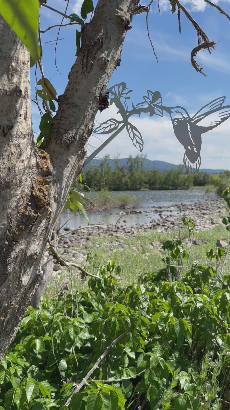 Metal hummingbird tree stake sipping from flower, rustic steel garden decoration for outdoor yard or planter