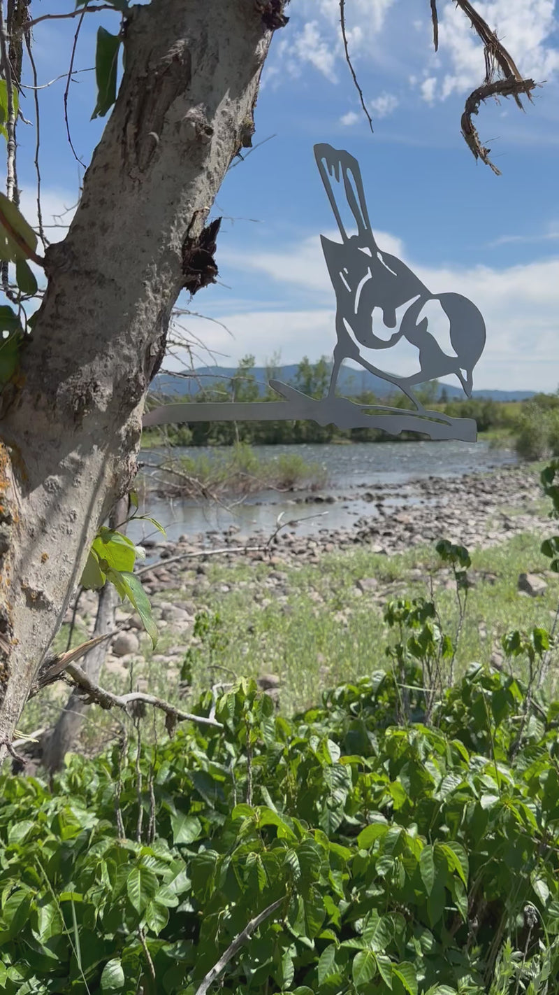 Metal finch bird tree stake perched on branch, rustic steel garden decoration for outdoor yard or flower bed