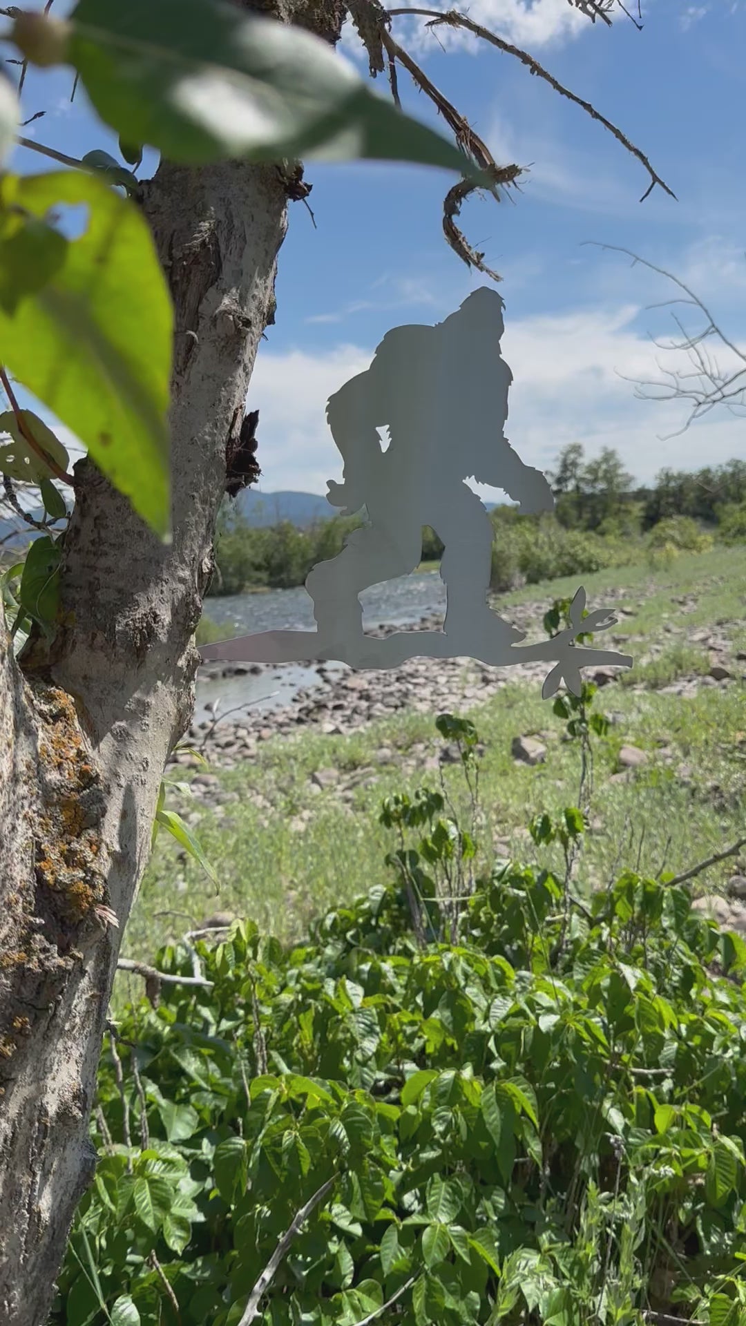 Load video: Metal sasquatch tree stake on branch, rustic steel Bigfoot garden decoration for outdoor yard or lawn